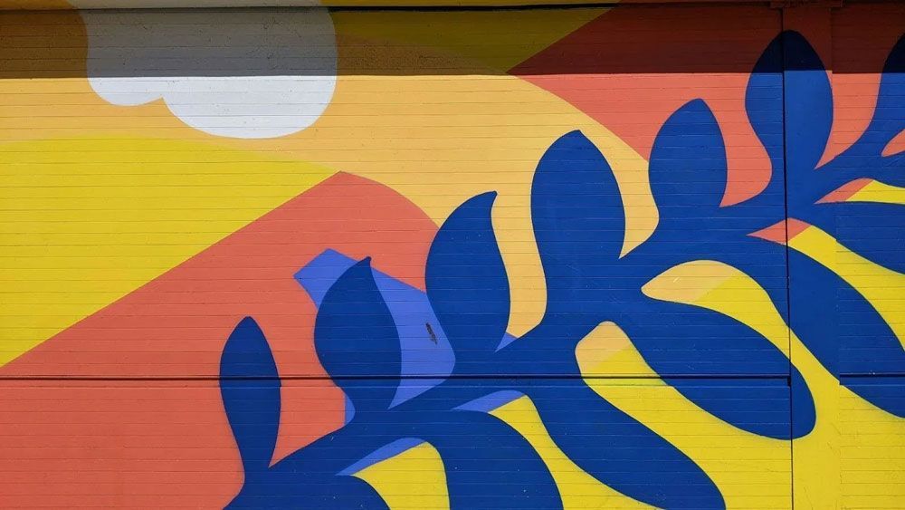 Colorful mural: Yellow, orange, and blue stylized landscape with leaves.