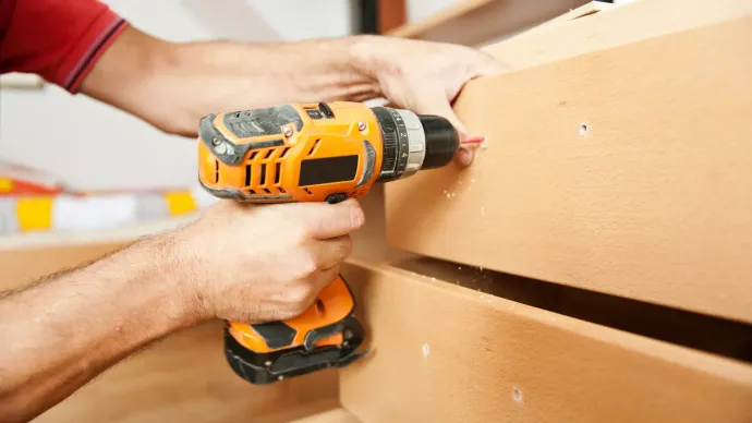 A man is using a drill on a piece of wood.