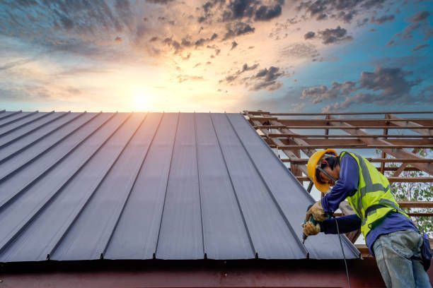 The roofer carefully secures metal sheets using a drill and roofing tools.