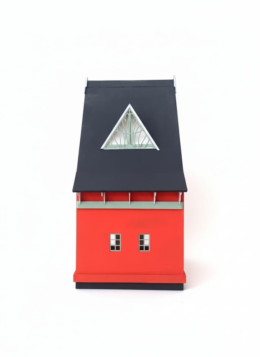Modelo de edificio de color rojo y negro con una ventana triangular en el techo, sobre un fondo blanco.