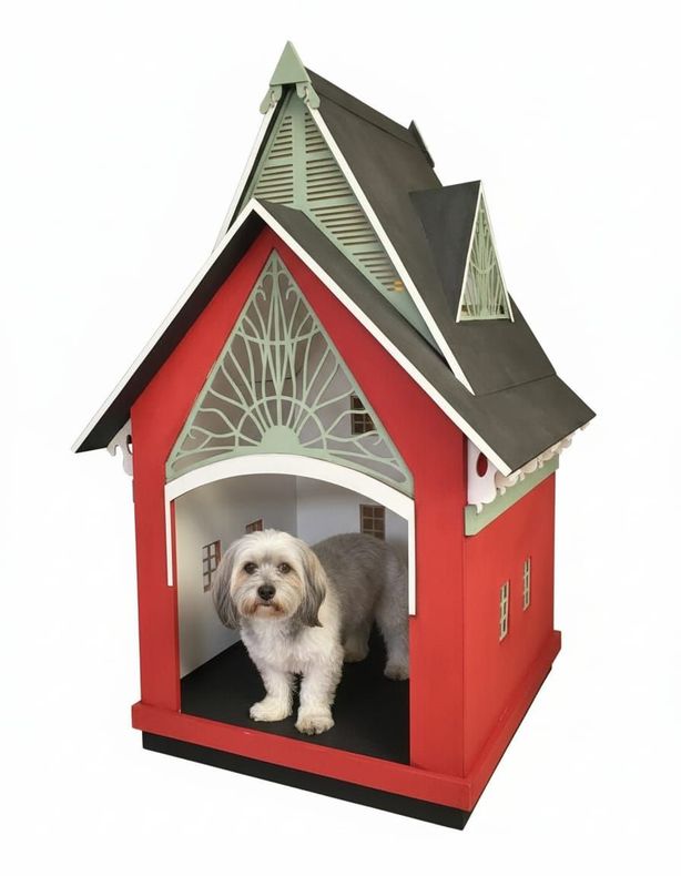 Perro en una caseta roja brillante con frente decorativo. Detalles verdes y techo oscuro.