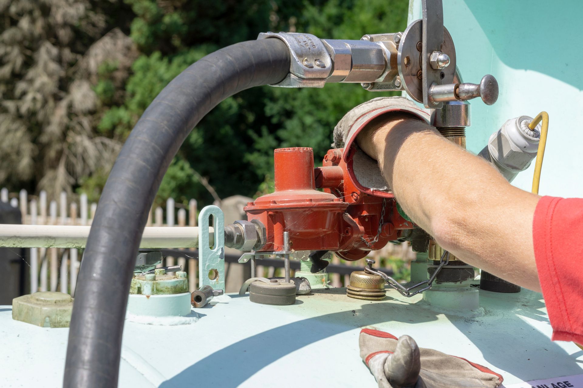 Close-up of a person filling a light blue domestic gas tank under the sun