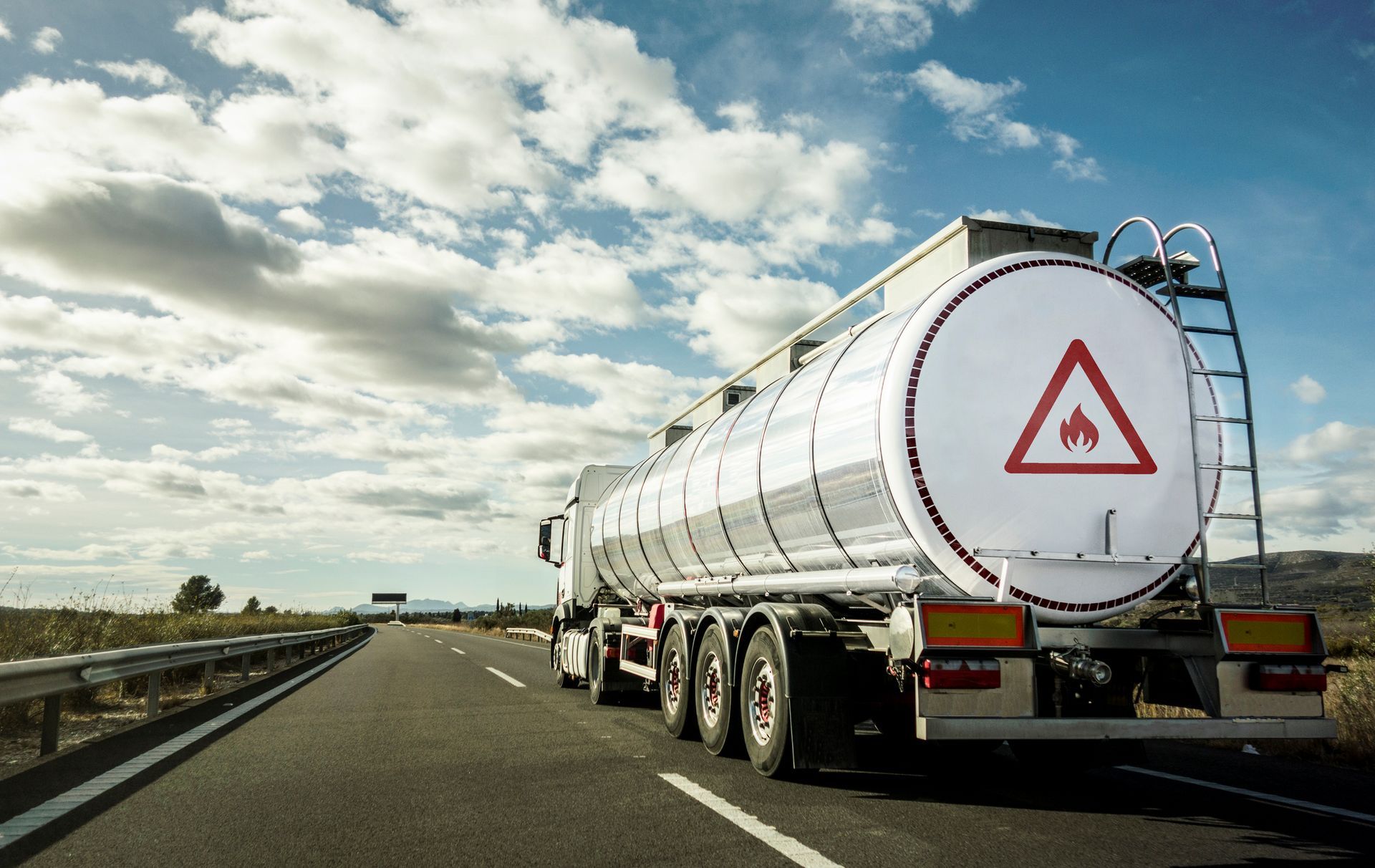 A white tanker truck, used by a gasoline distributor, is transporting gasoline by road.