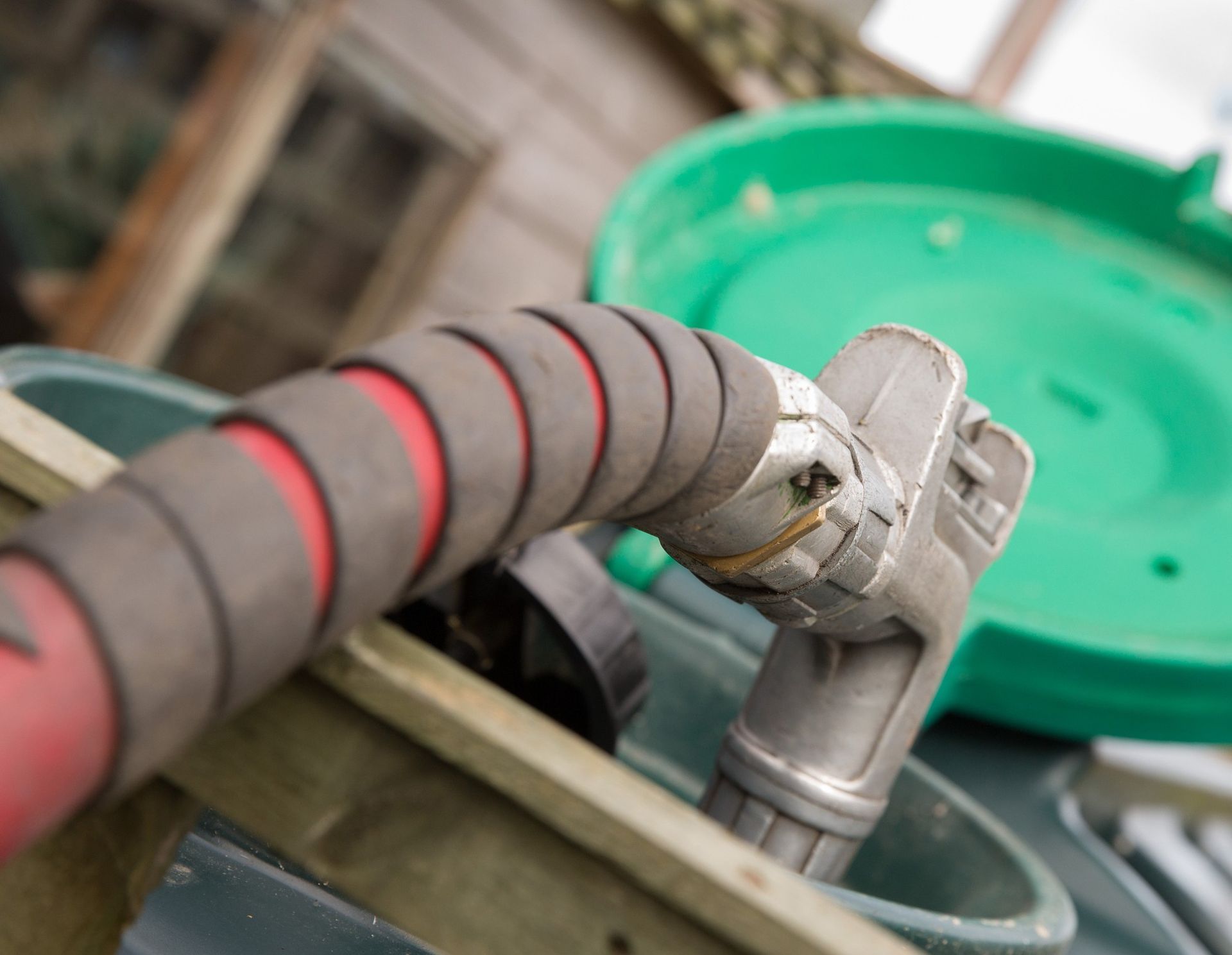Close-up of a fuel hose nozzle attached to tank equipment for industrial liquid transfer used daily.