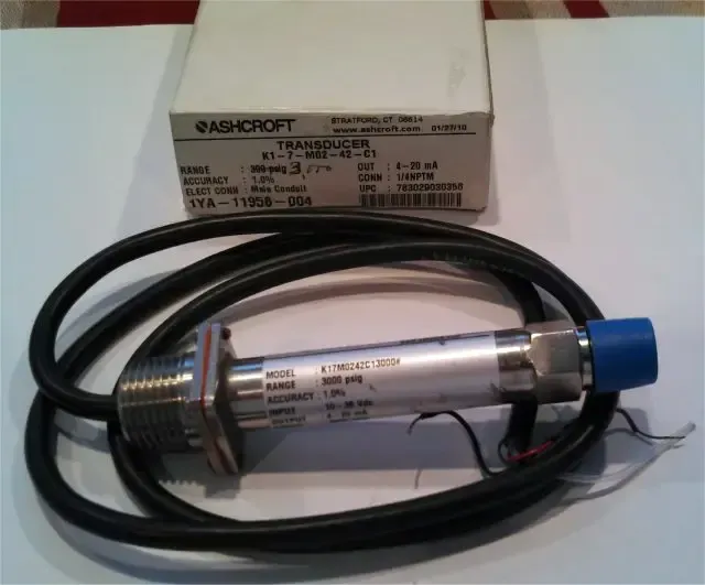 Coiled black cable with a silver cylindrical sensor and blue cap beside a small labeled box