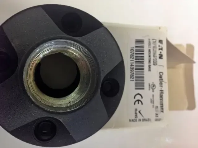 Close-up of a black metal circular connector with a threaded center and white product label