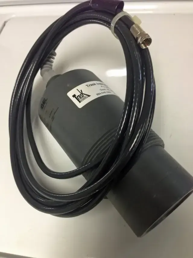 Black cable coiled around a gray cylindrical device with a connector on top