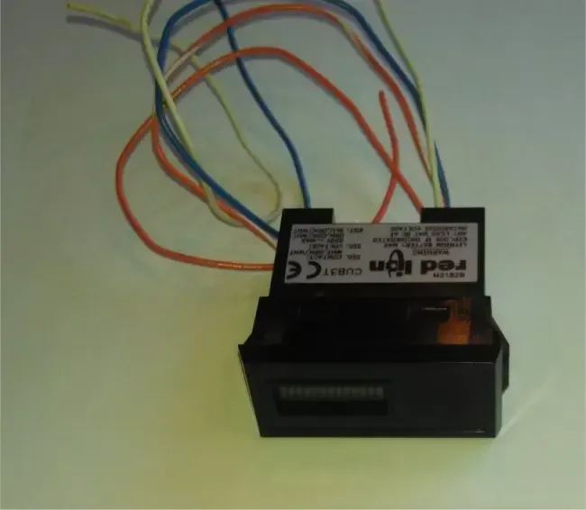 Black electronic module with multicolored wires attached against a light background