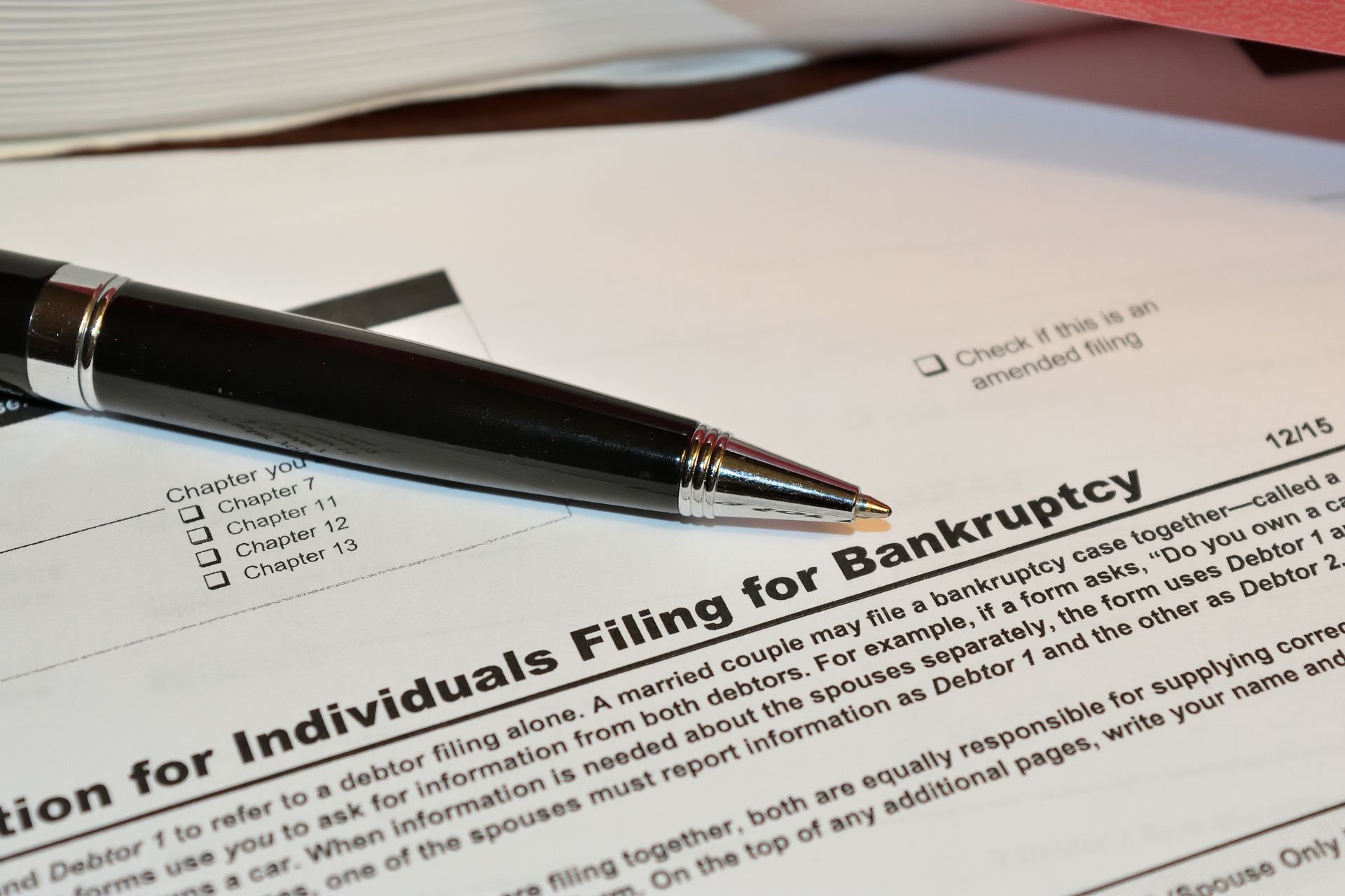 Close-up of a bankruptcy filing form with pen and legal documents, representing debt relief. Close-up of a bankruptcy filing form with pen and legal documents, representing debt relief.