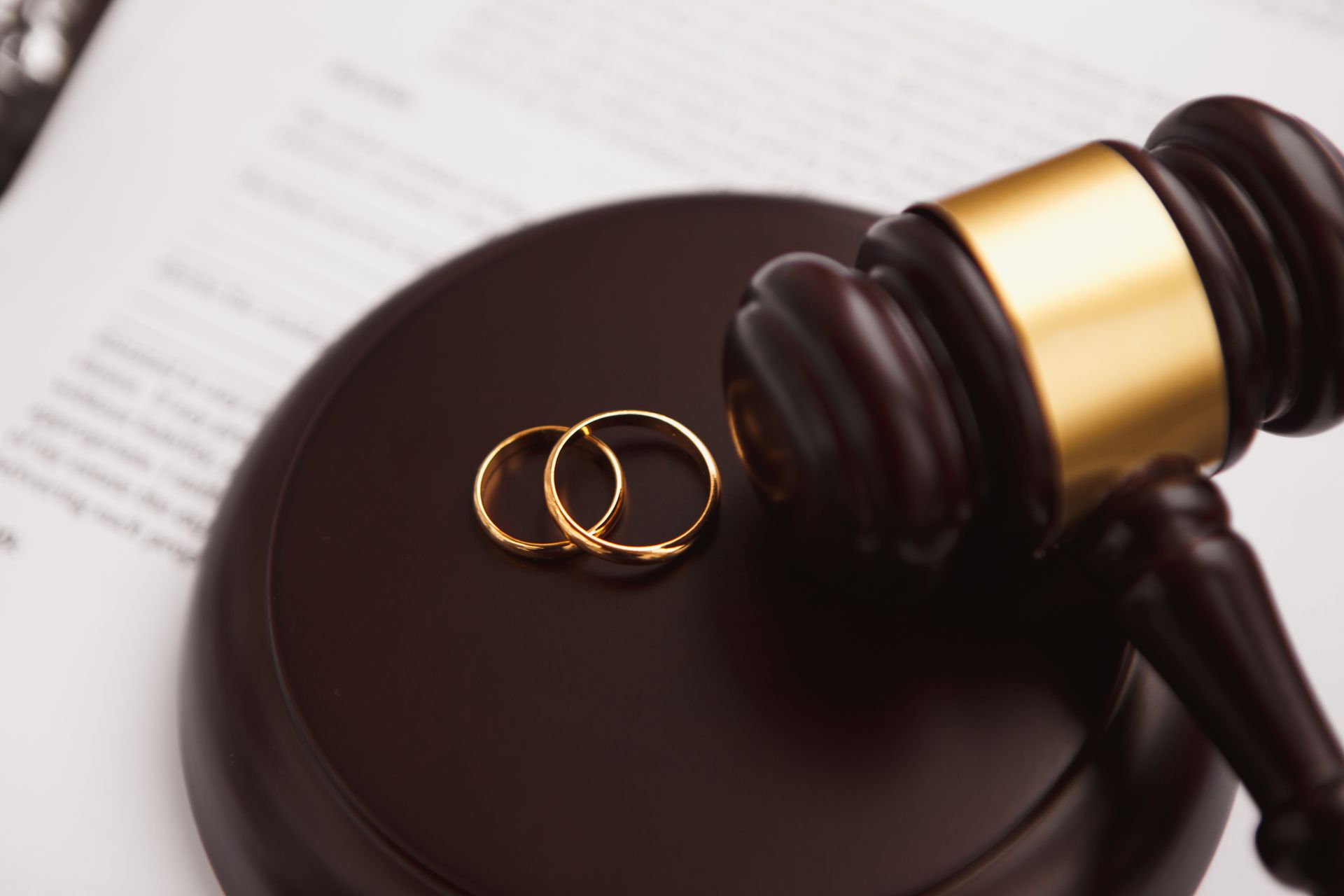 Gavel and wedding rings on a legal document representing professional divorce lawyer services. Gavel and wedding rings on a legal document representing professional divorce lawyer services.