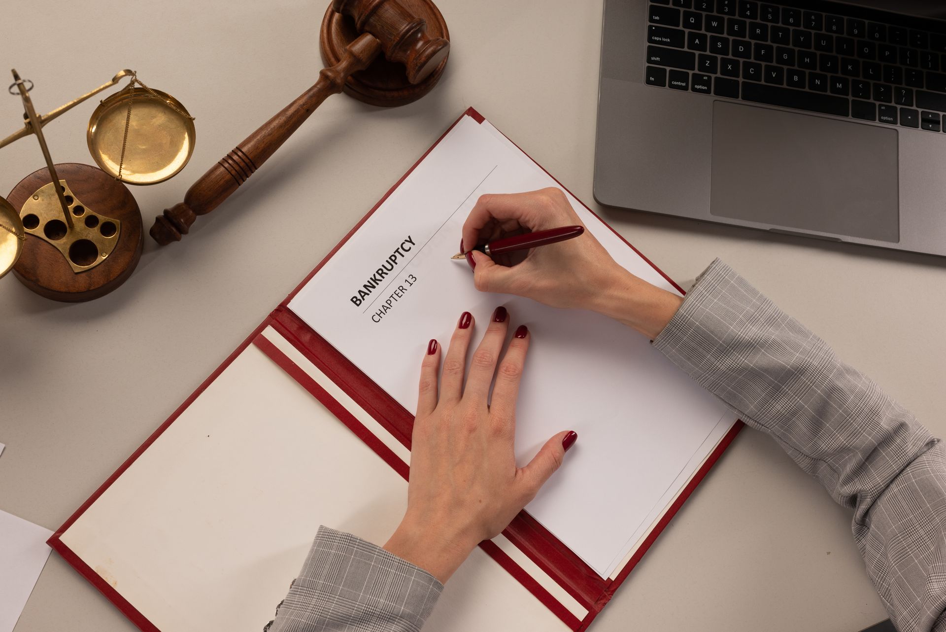 Person completing bankruptcy paperwork at a desk with legal documents. Person completing bankruptcy paperwork at a desk with legal documents.