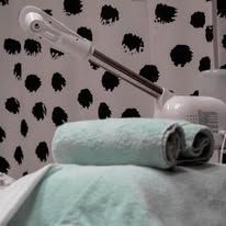 Steamer and rolled aqua towel on a table, against a black and white polka dot wall.