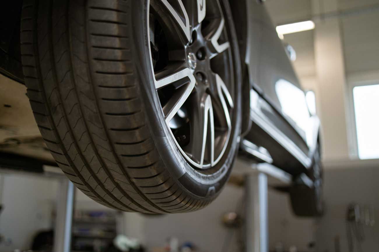 Close-up of a car raised on a hydraulic lift during a professional wheel alignment
