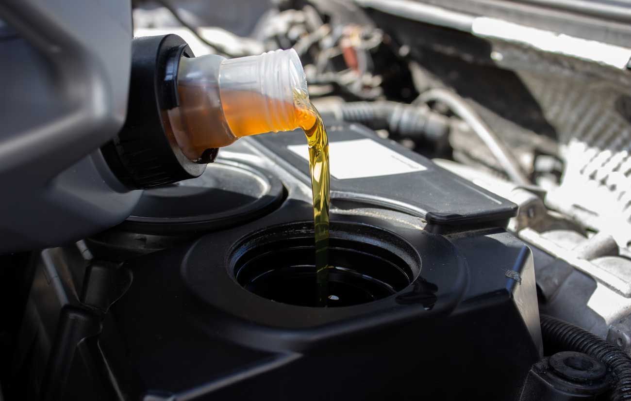 Close-up of fresh motor oil pouring from a can during an oil change