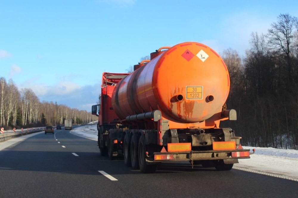A Large Orange Tanker Truck Is Driving Down A Highway — Nielson Diesel Mechanics in Swan Hill, VIC