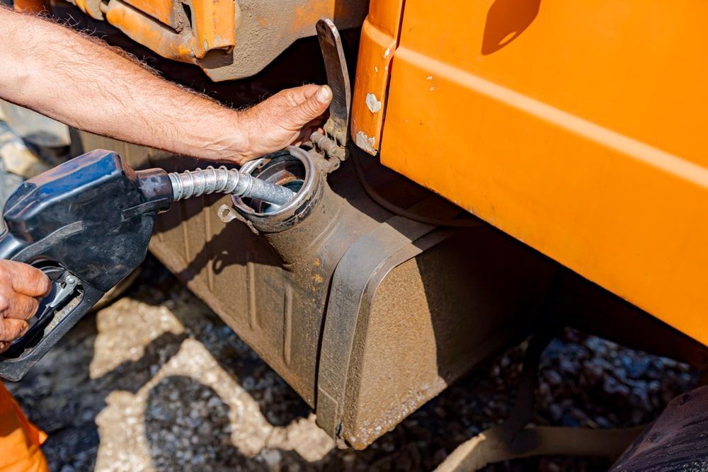 A Man Is Pumping Gas Into An Orange Truck — Nielson Diesel Mechanics in Swan Hill, VIC