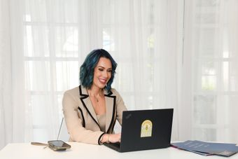 A group of people are sitting around a table with laptops.