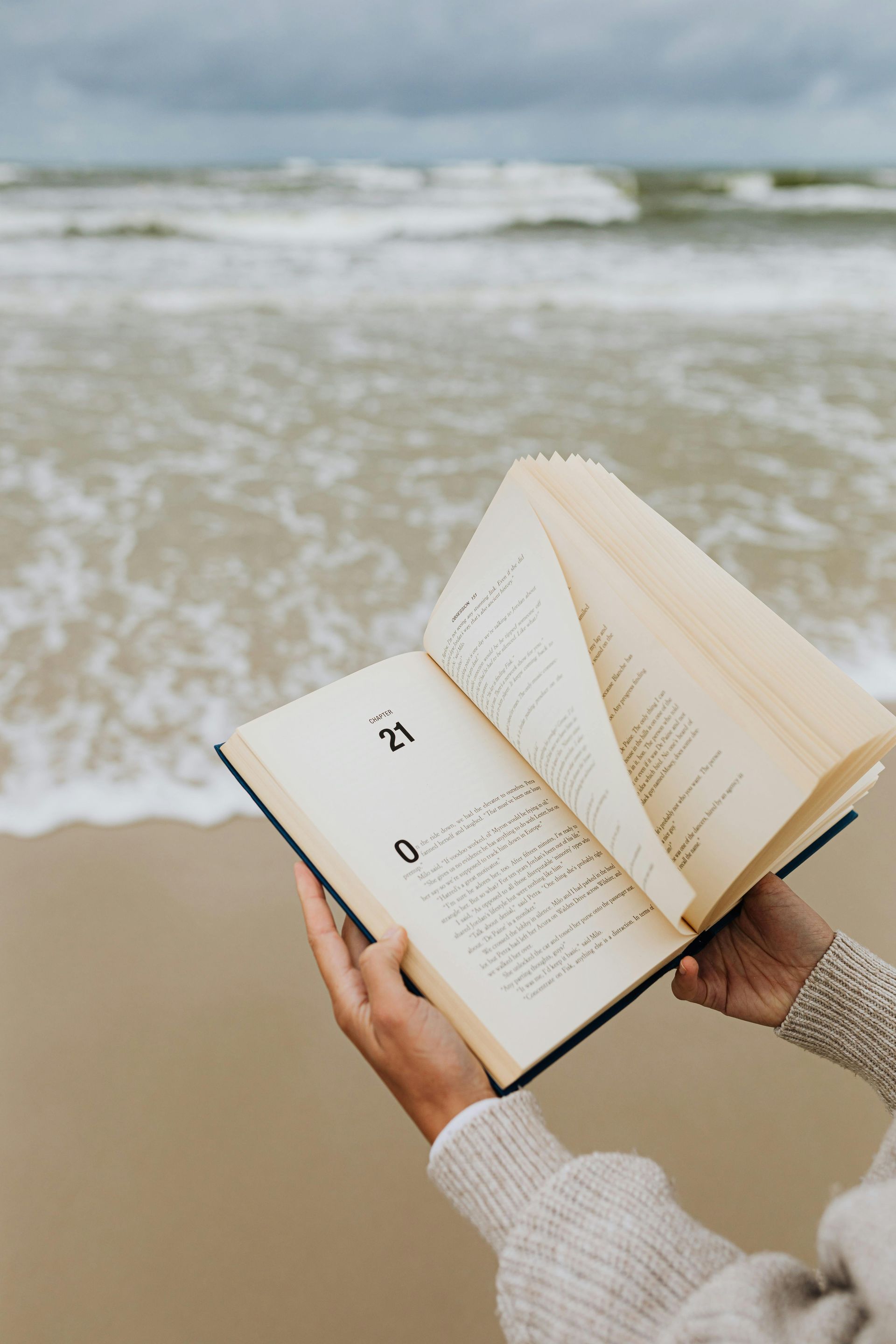 A person is reading a book on the beach.