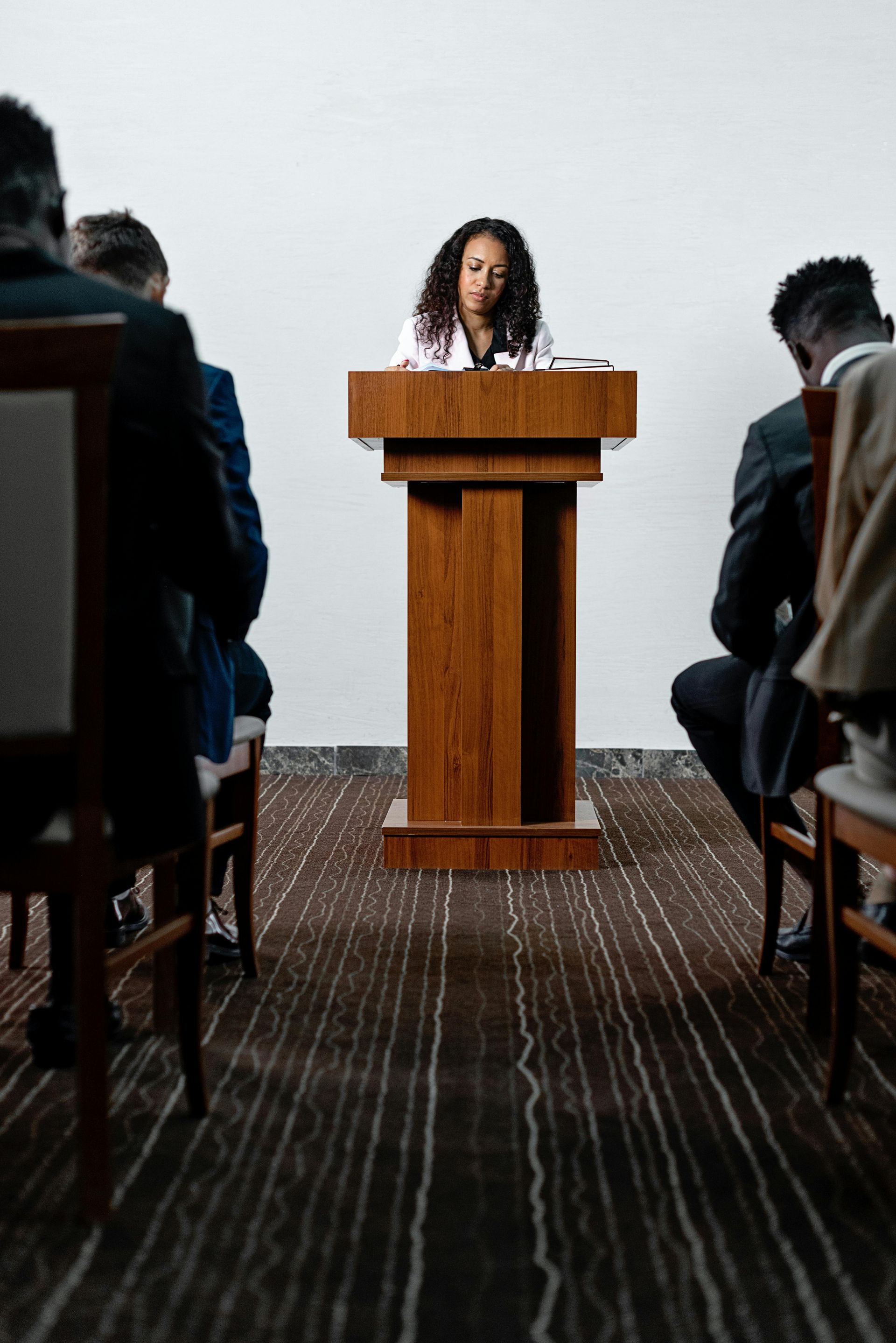 A woman is giving a speech at a podium in front of a group of people.