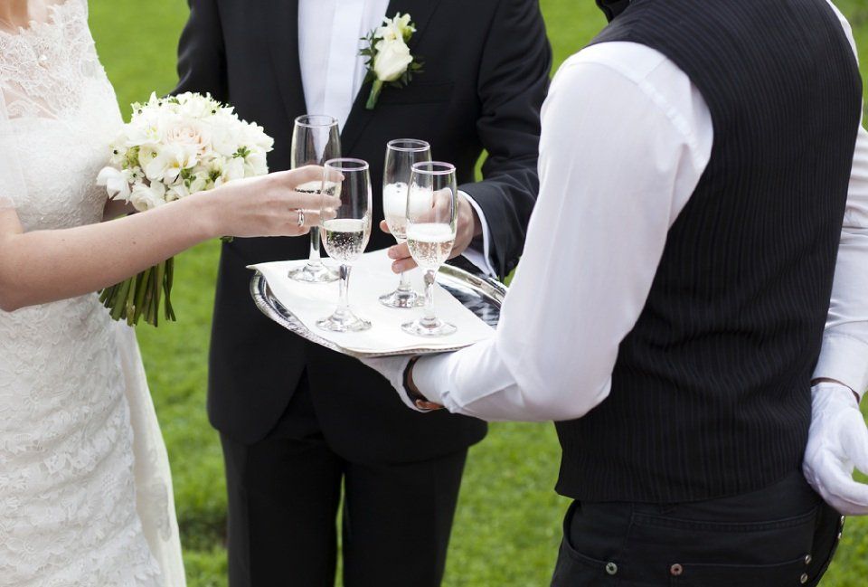 waiter serving white wine to bride and groom