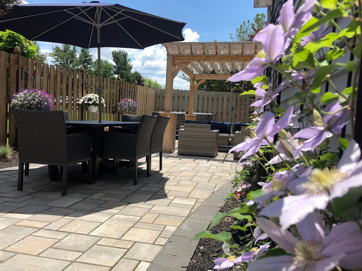 Patio with dining set, pergola, and flowering vines on a sunny day.