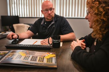 Man and woman seated at a desk, reviewing paperwork and a brochure. The man has a mug that says 
