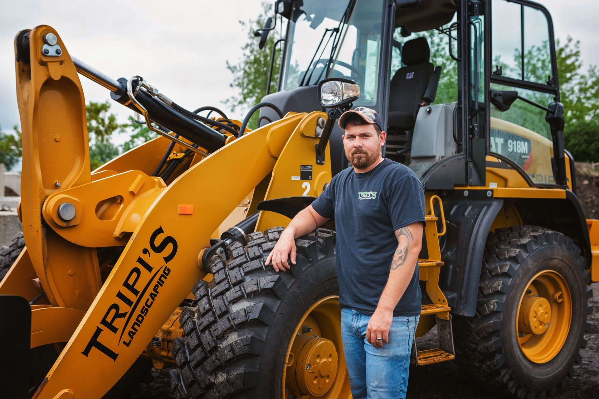 Man in work clothes leaning against a yellow construction loader with 