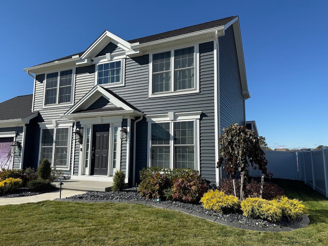 A backyard garden with a wooden fence, greenery, stone bench, and lush green lawn.