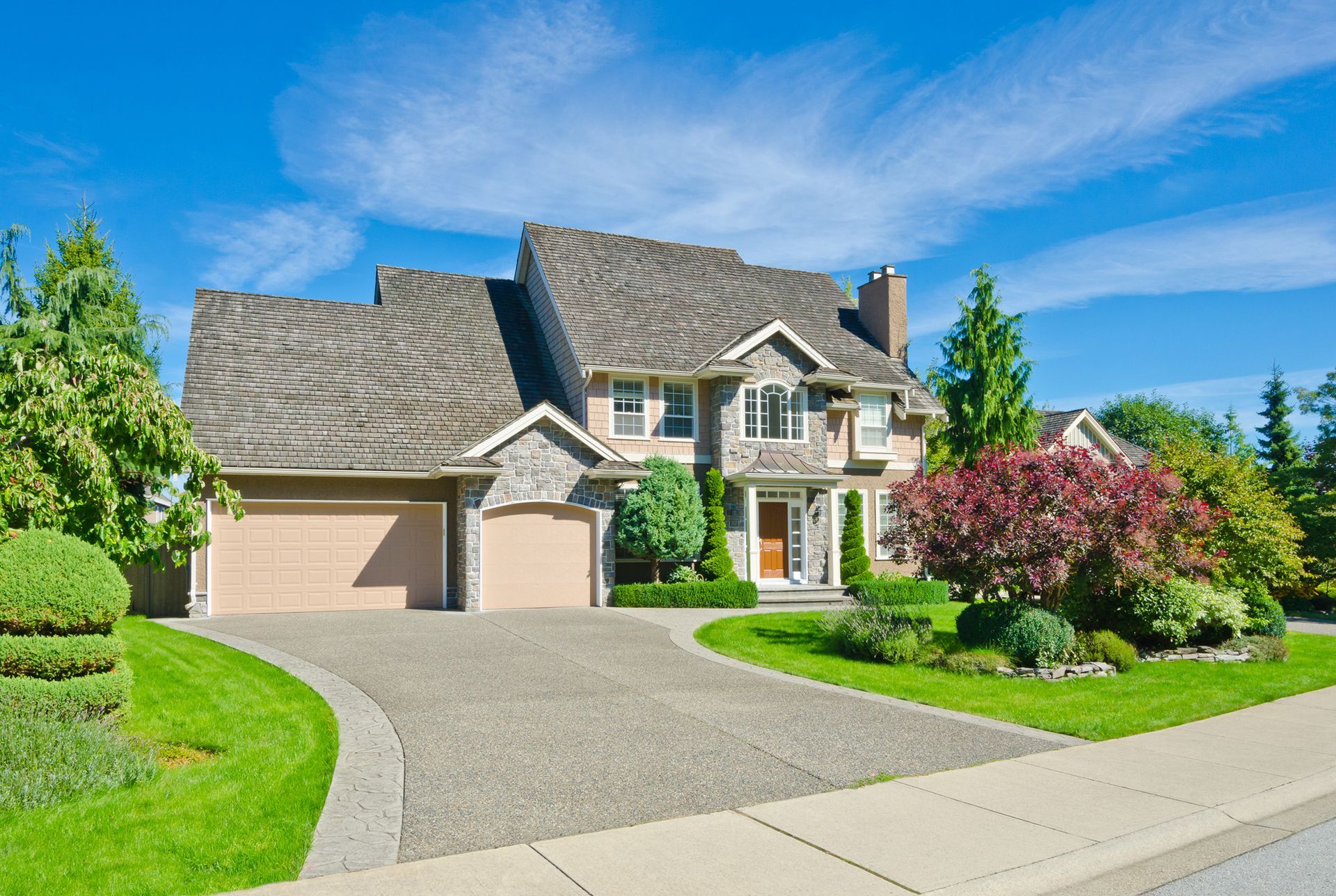 Two-story house with a driveway, green lawn, and blue sky.