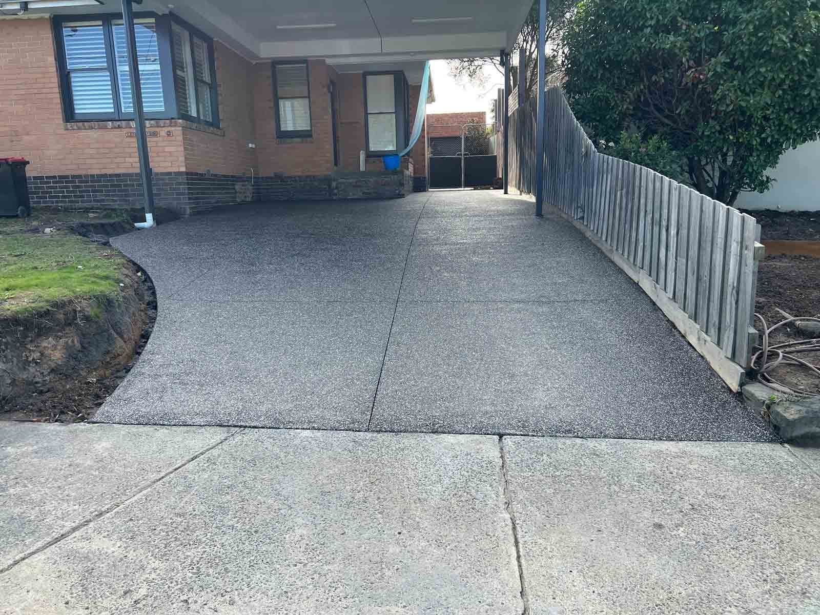 A concrete driveway leading to a house with a carport