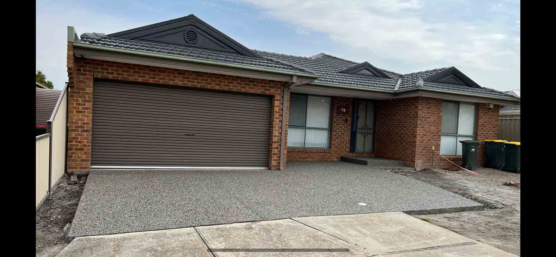 A brick house with a garage door and a gravel driveway