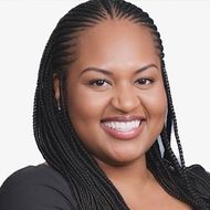 A woman with braids is smiling and wearing a black shirt.