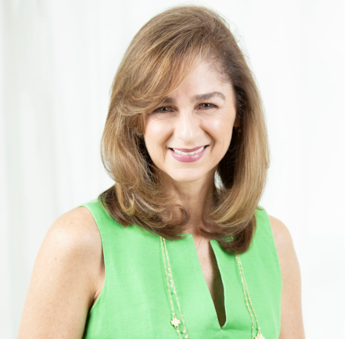 A woman in a green top is smiling for the camera