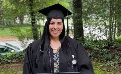 A woman and a child are sitting on a couch looking at a laptop.