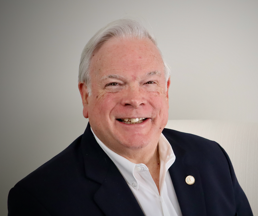 A man in a suit and white shirt is smiling for the camera.