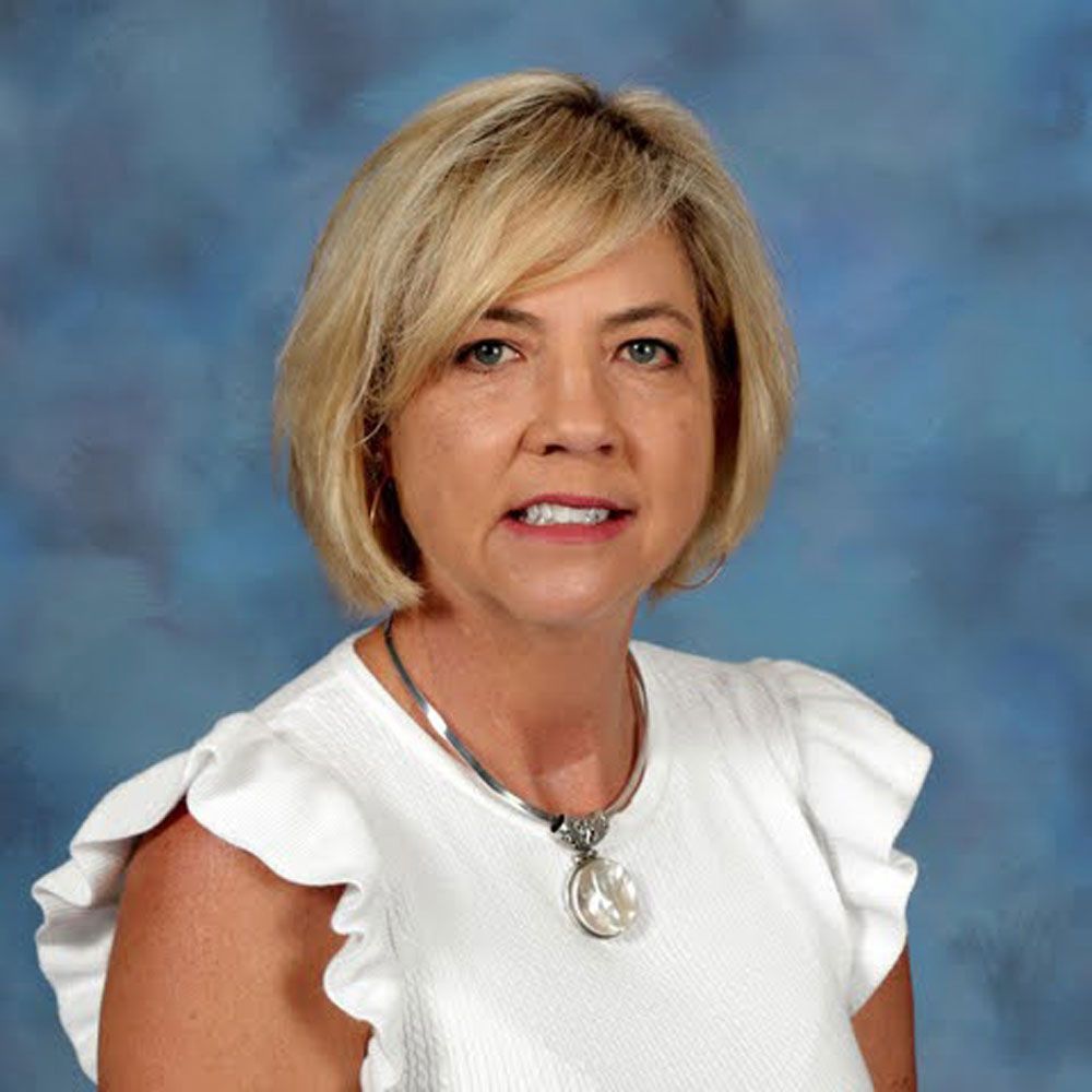 A woman wearing a white shirt and a necklace is posing for a picture.
