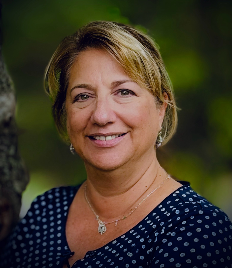 A woman in a blue polka dot shirt is smiling for the camera.