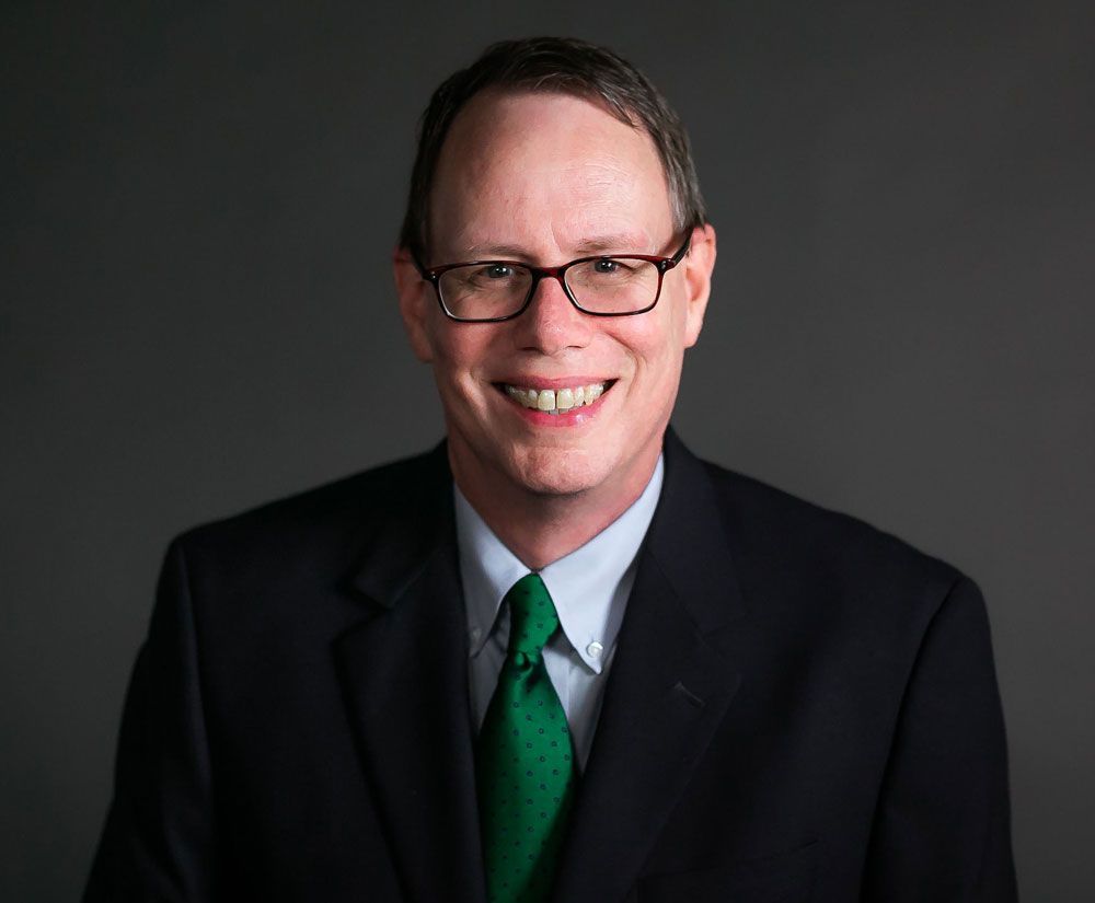 A man in a suit and tie is smiling for the camera.