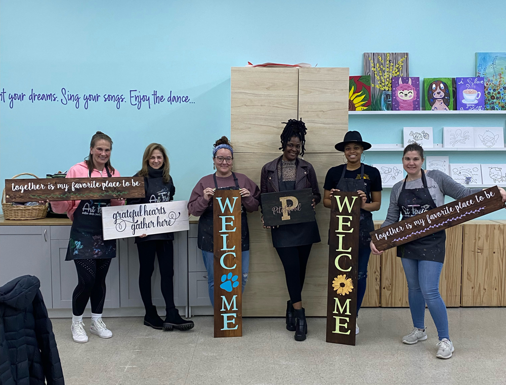 A group of women are standing next to each other holding wooden signs.