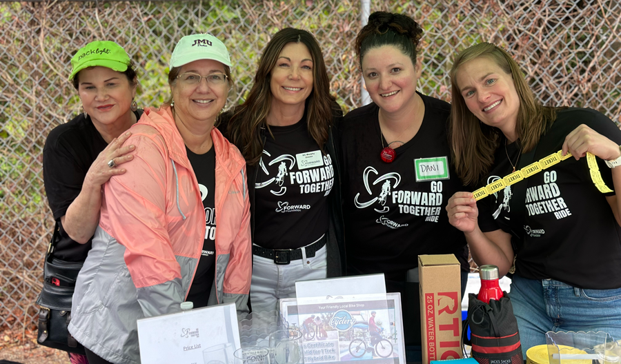 A group of women are posing for a picture in front of a table.