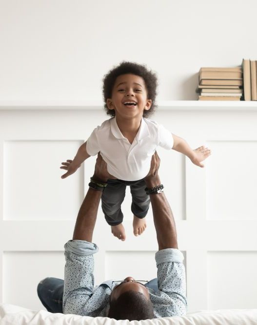 A man is holding a little boy in the air.