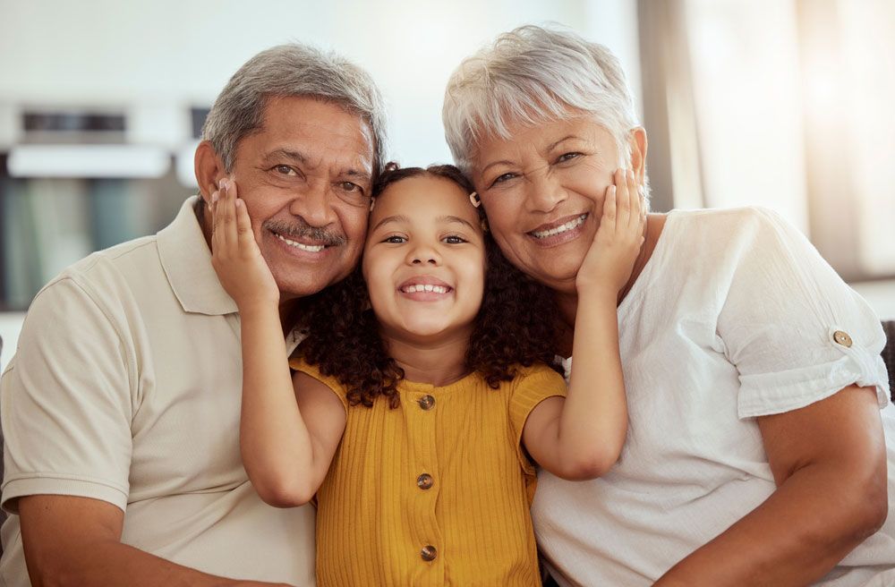 A little girl is posing for a picture with her grandparents.