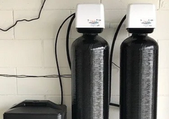 two black water filters are sitting next to each other on a white brick wall .