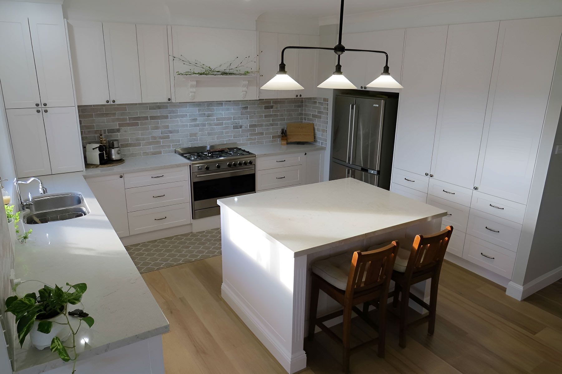 Kitchen With White Cabinets, a Central Island, and Wooden Floors — Piscopo Kitchens Plus In Forster, NSW