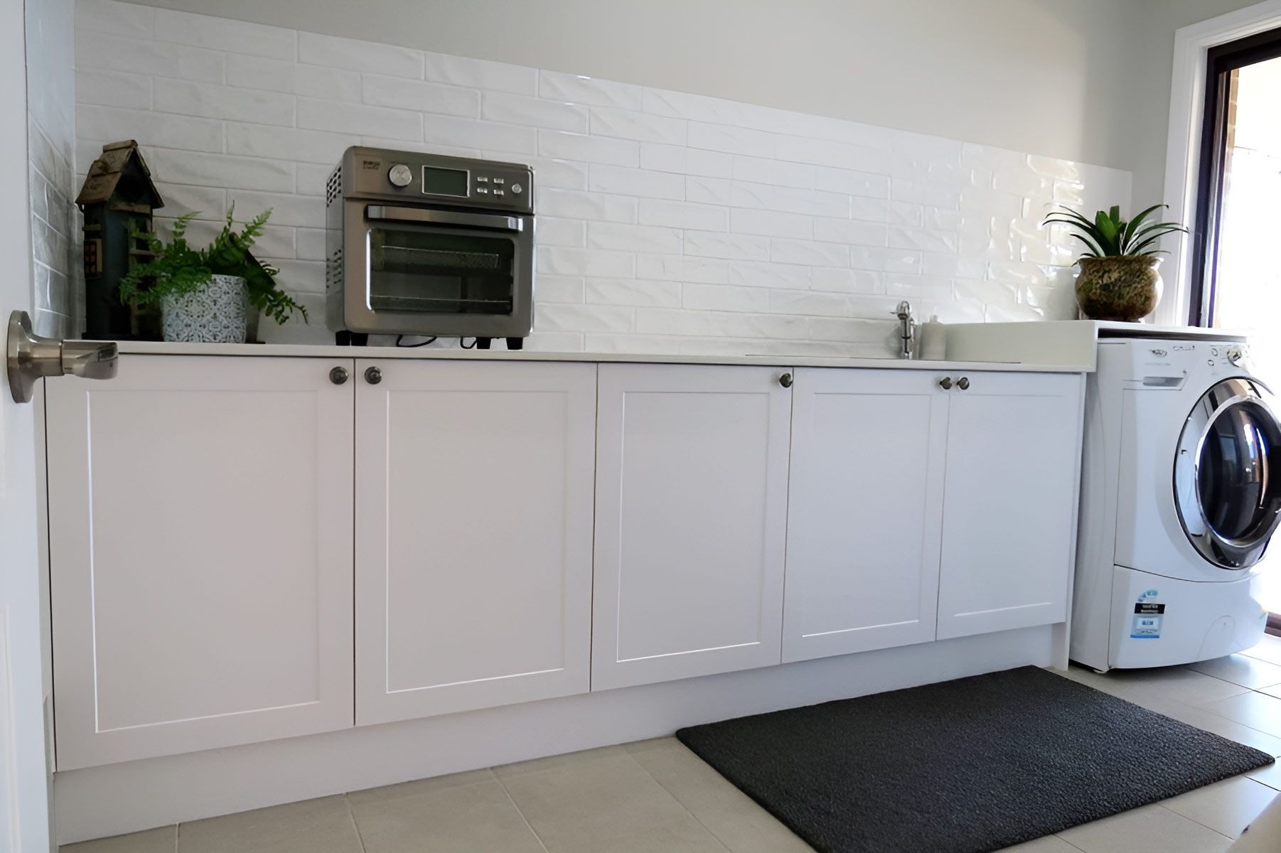Laundry Room With White Cabinets and a Tiled Backsplash — Piscopo Kitchens Plus In Forster, NSW