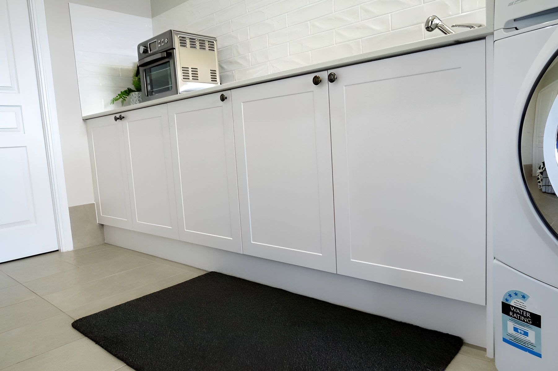 Laundry Room With White Cabinets and a Washing Machine — Piscopo Kitchens Plus In Forster, NSW