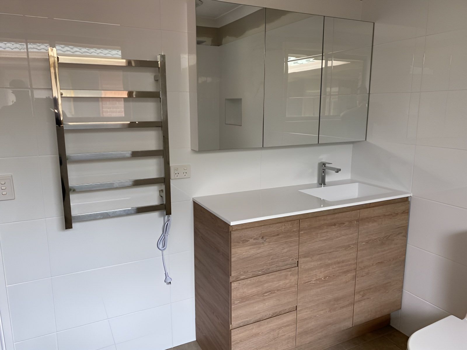 A Modern Bathroom With a Wall-mounted Chrome Towel Rack — Piscopo Kitchens Plus In Forster, NSW