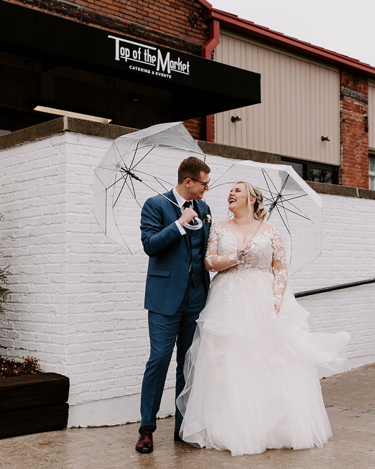 bride and groom under clear umbrellas