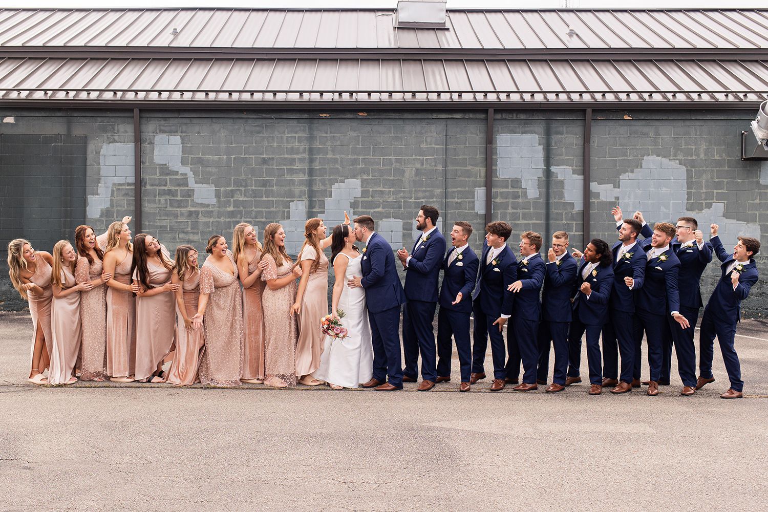 bride and groom kissing surrounded by wedding party