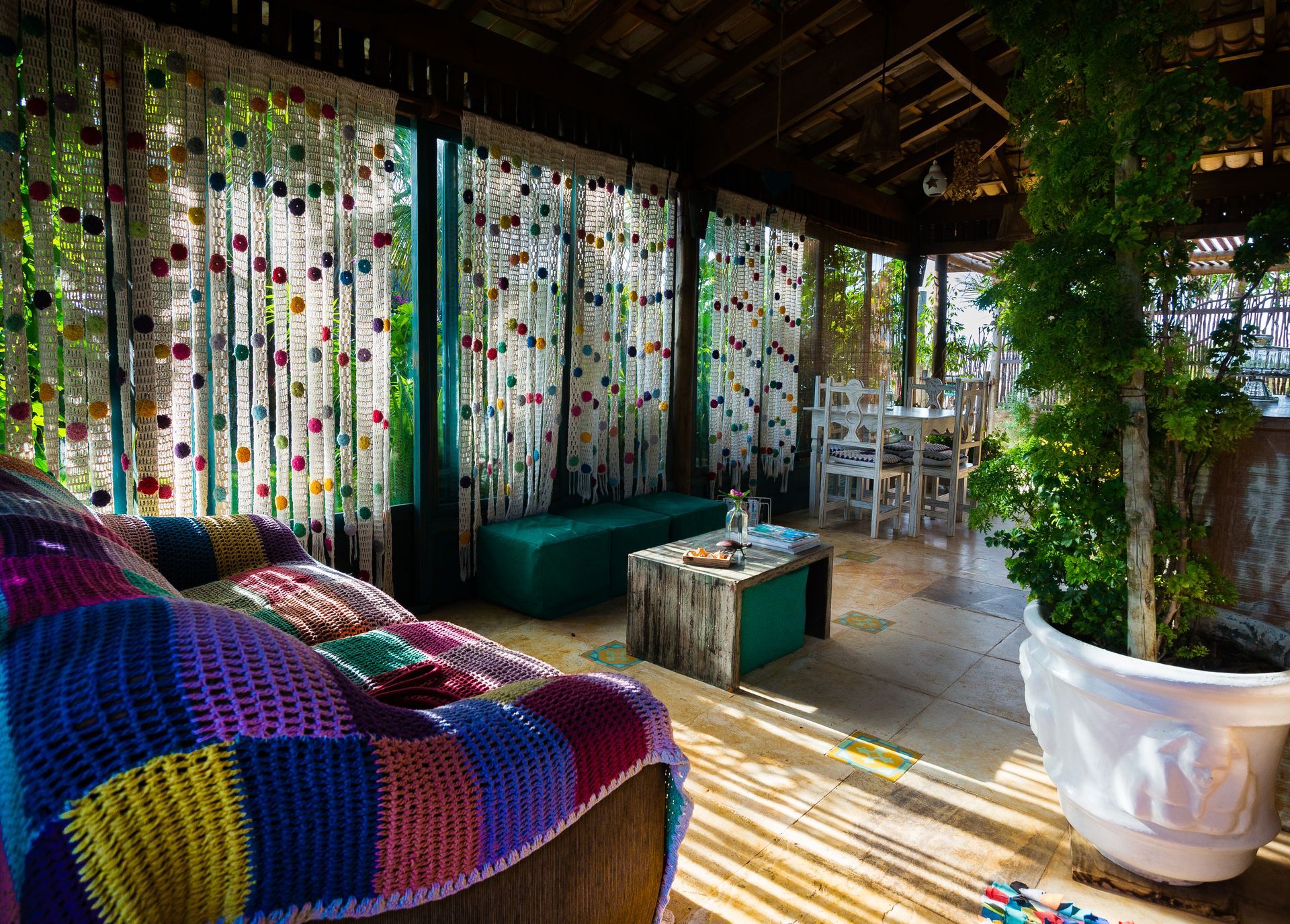 Uma sala de estar com um sofá colorido e uma planta em vaso.